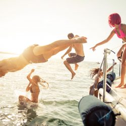 group of friends diving in the water during a boat excursion