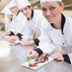 Smiling Chef's finishing dessert plates in the kitchen