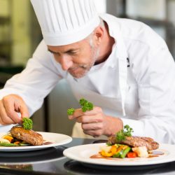 Closeup of a concentrated male chef garnishing food in the kitchen